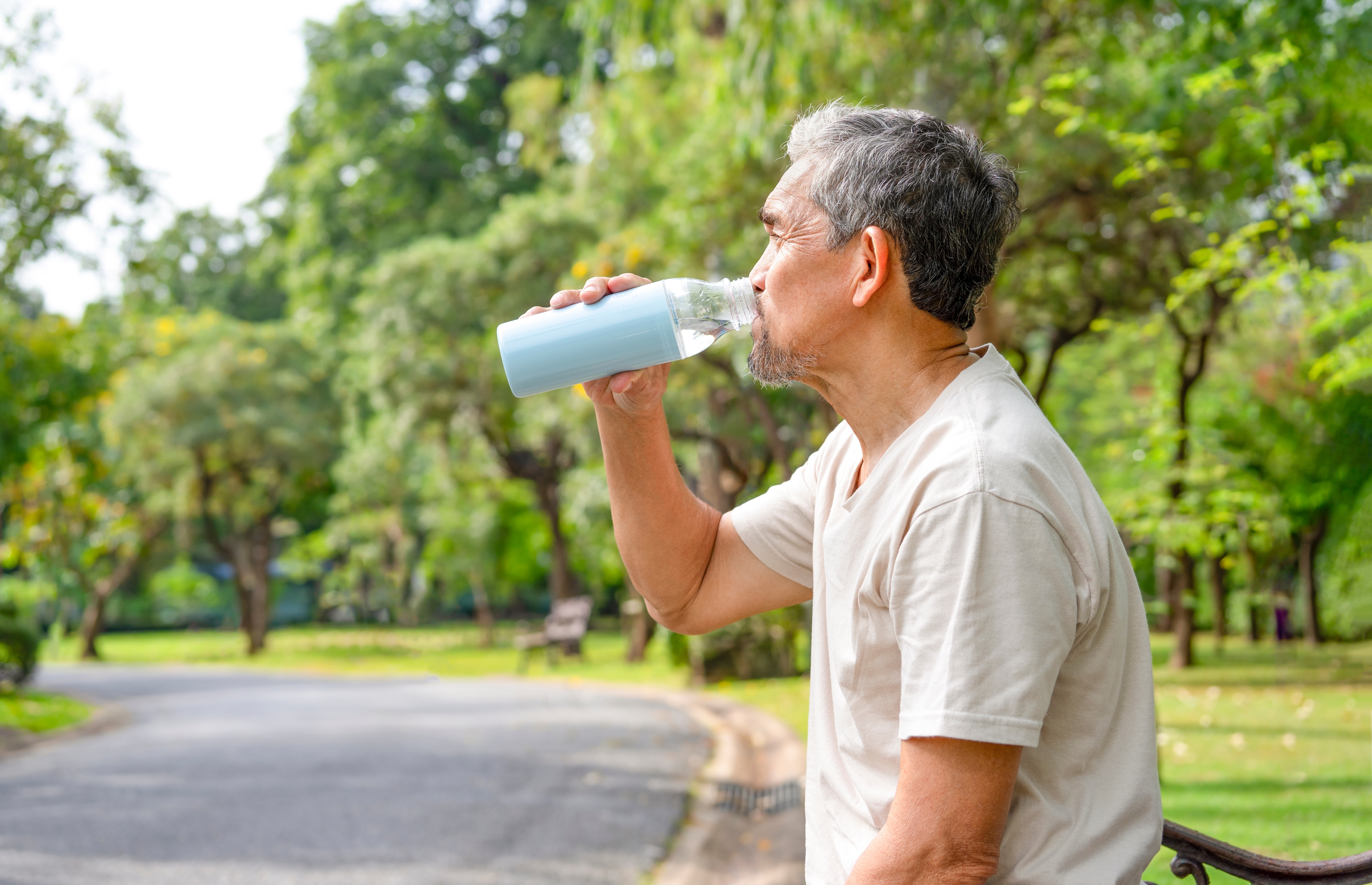 senior man drinking water after workout in the park for body refreshment, concept adult older drinking water substitutes while exercising